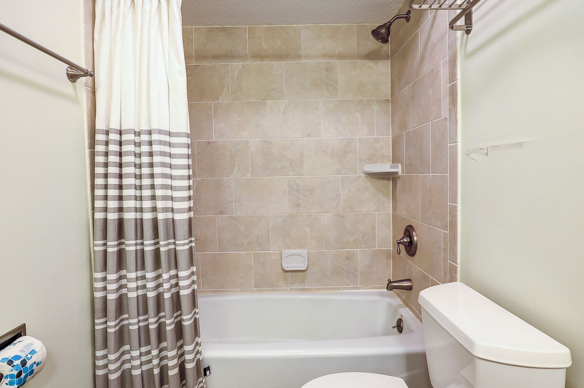 Un baño con bañera, inodoro y cortina de ducha.