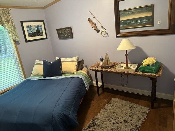 A bedroom with a bed, a nightstand, a lamp, and wall art.