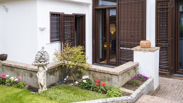 A modern building with large windows, a small garden with flowers, and a statue. - House Garden San Lorenzo (Salerno)
