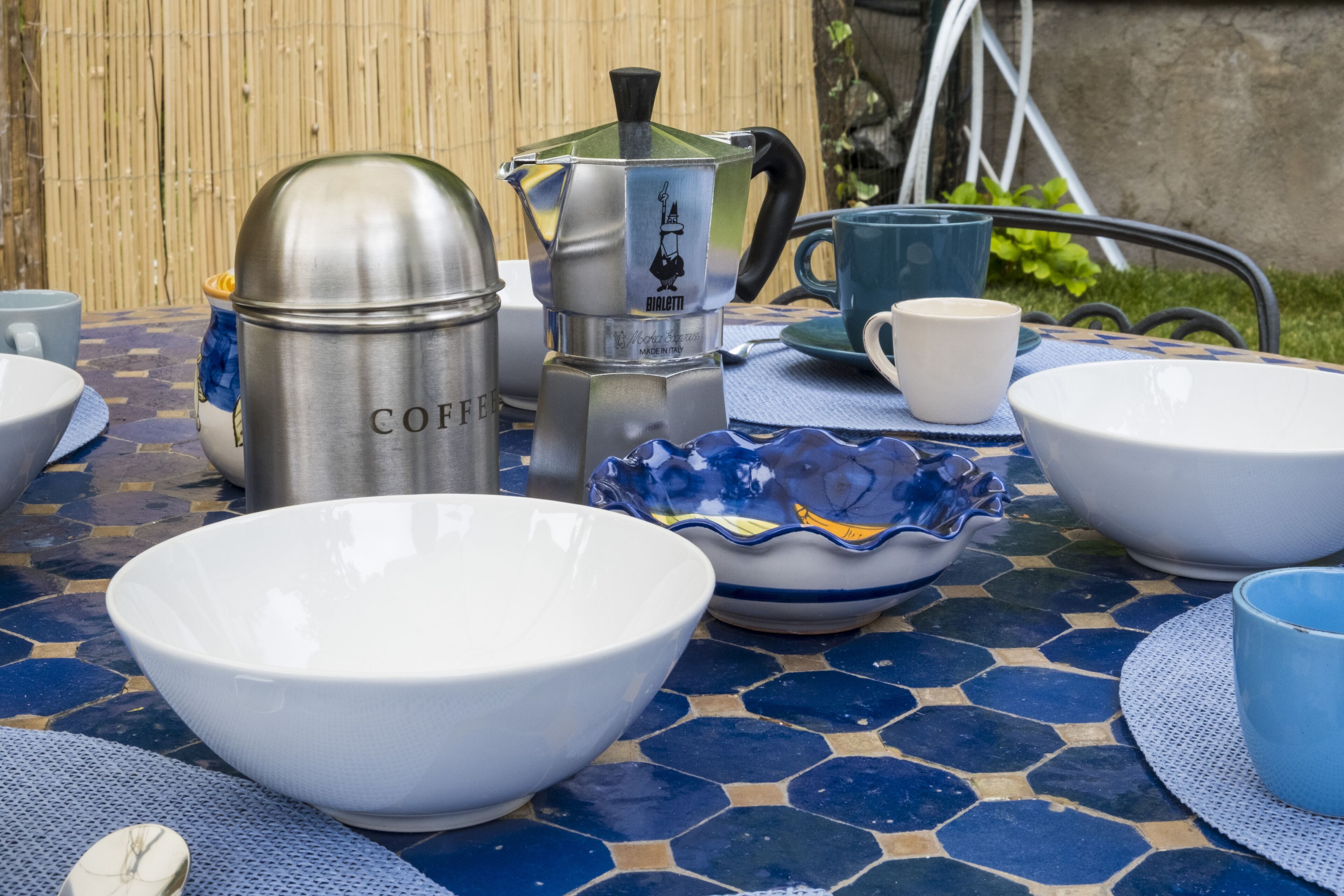 Een tafel met divers keukengerei, zoals een koffiezetapparaat, kommen en bekers.