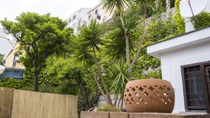 A courtyard with a large terracotta pot, a wooden fence, and lush greenery. - House Garden San Lorenzo (Salerno)