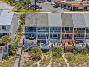 A multi-story building with balconies, a parking lot, and a beachside location.