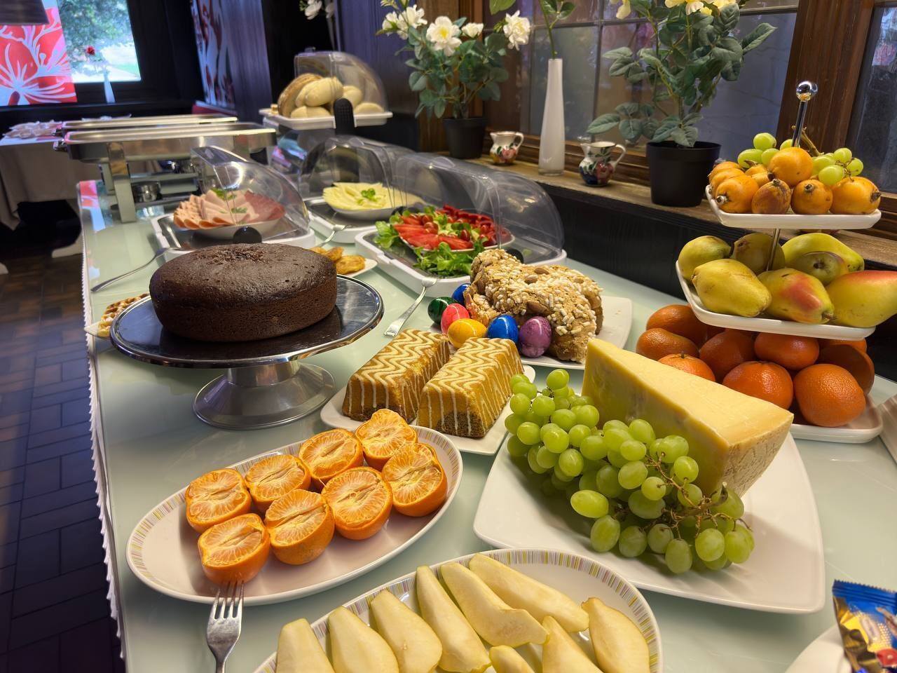 Un bufé con diversas opciones de comida, incluyendo pasteles, frutas y quesos.