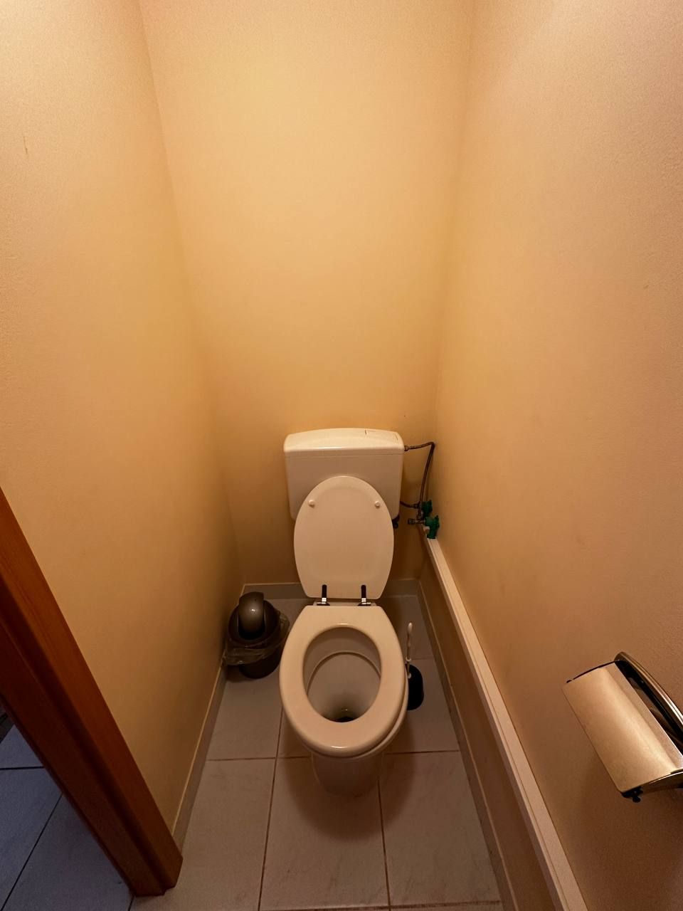 Uma casa de banho pequena com sanita, bidé e suporte para papel higiénico.