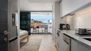 Eine kompakte Küche mit modernen Geräten, ein Essbereich mit Aussicht und ein Balkon mit einem Bett.
