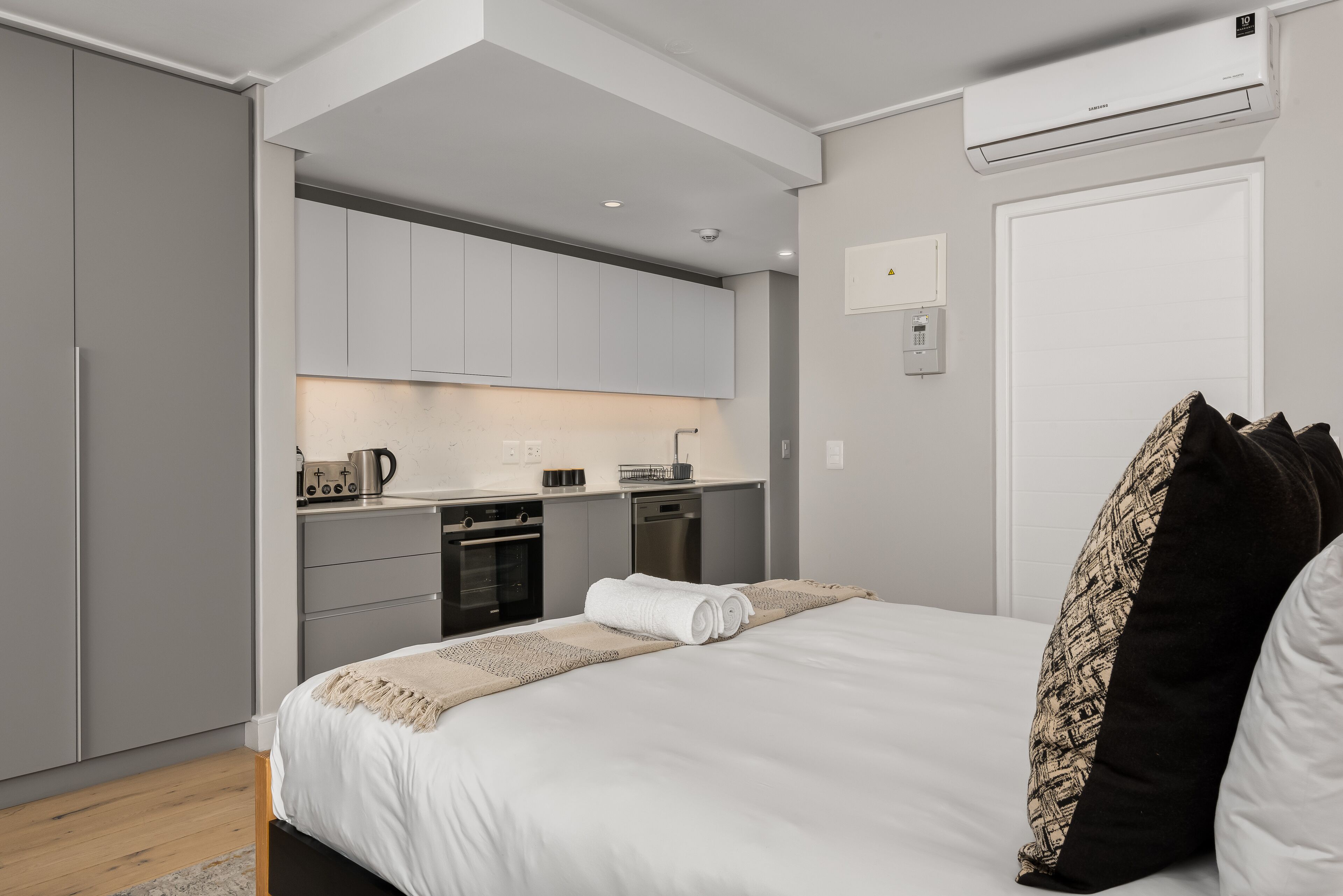 Een moderne hotelkamer met een bed, een klein kitchenette en een badkamer.