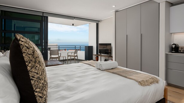Ein modernes Hotelzimmer mit einem großen Bett, einem Schreibtisch und Blick auf den Ozean.