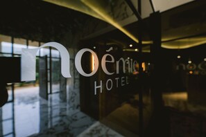 A hotel entrance with a modern design, featuring a glass facade and a prominent sign.