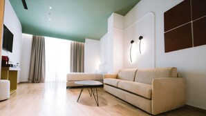 A modern living room with a beige sofa, a round coffee table, and a wooden floor. - Hotel Noemie (Himarë)