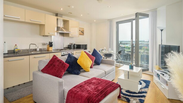 A modern apartment with a kitchen, living area, and large windows offering a city view. - Charming 1-bed Apartment in Leeds (Leeds)