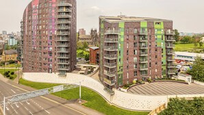 A modern apartment complex with curved balconies, a central courtyard, and a view of a historic church in the background. - Charming 1-bed Apartment in Leeds (Leeds)