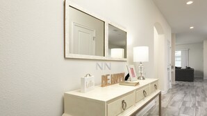 A modern bathroom with a vanity, mirror, and decorative items. - Luxury 6BR Townhome with Private Pool, Game Room & Resort Access Near Disney (Kissimmee)