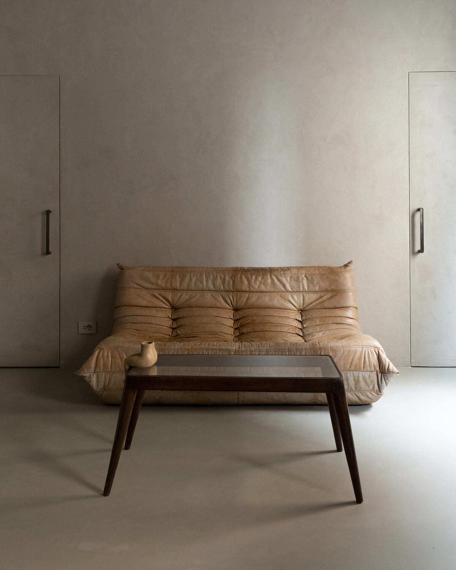 A minimalist room with a leather sofa and a wooden coffee table.