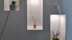 Three rectangular wall-mounted shelves with recessed lighting, each containing a different decorative item. - Himara 28 (Himarë)