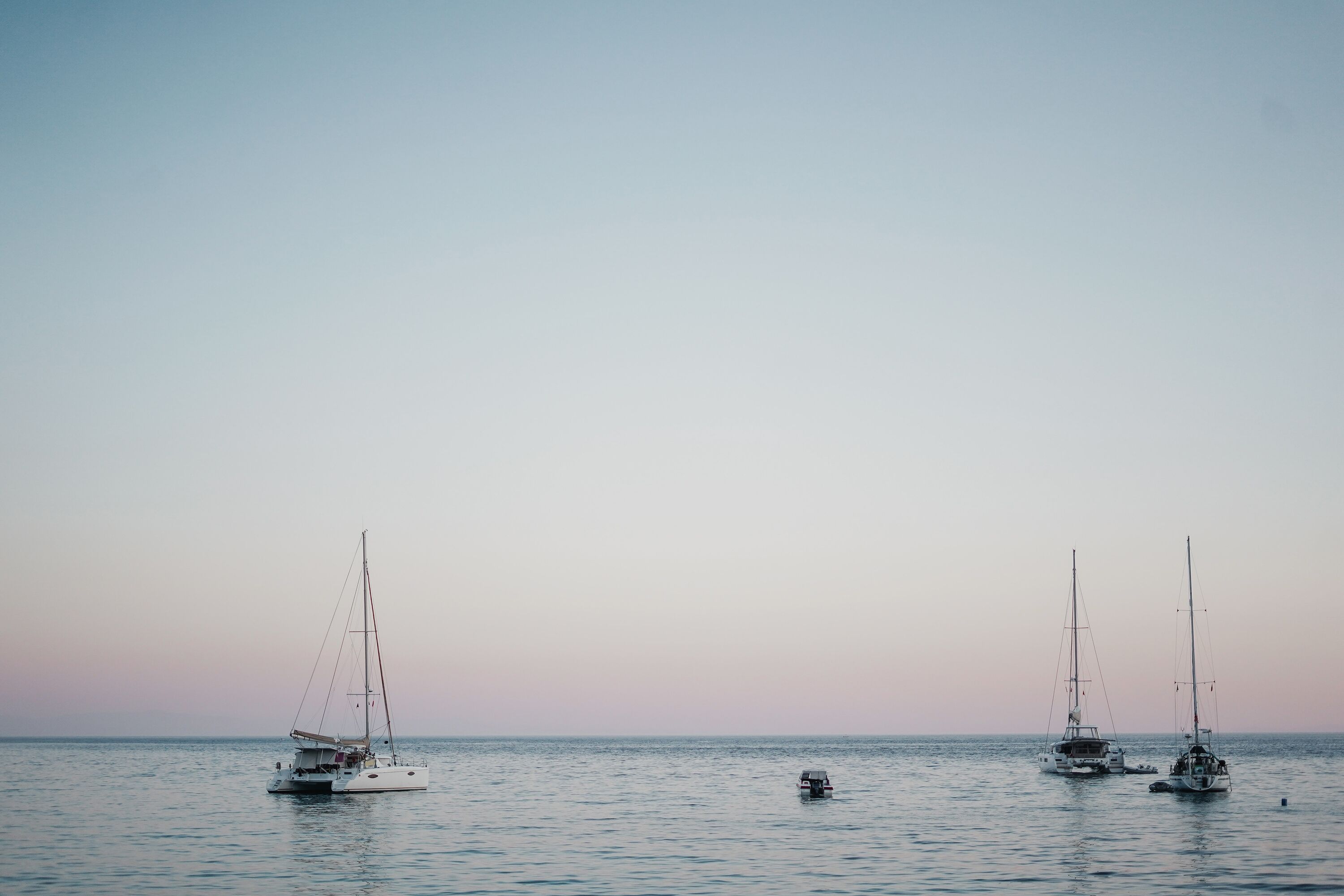 Three sailboats on calm water.