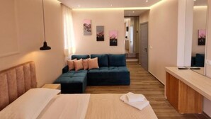 A modern bedroom with a large bed, a sofa, a desk, and a mirror. - Himara 28 (Himarë)