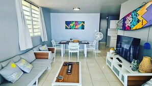 Un soggiorno moderno con divano, tavolino, mobile TV e zona pranzo con sedie e tavolo.