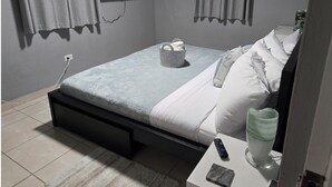 Una camera da letto con un letto, un comodino, un telecomando e una TV a parete.