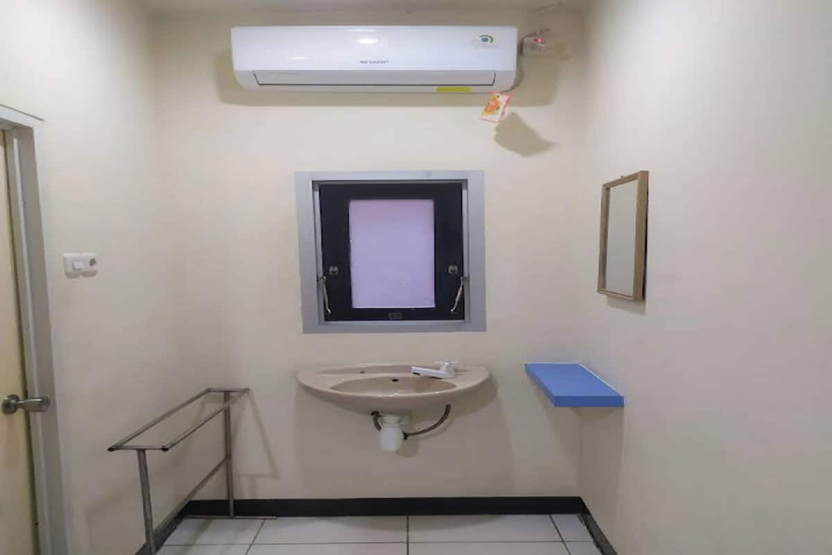 Une petite salle de bain avec un lavabo, un miroir et un climatiseur.