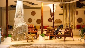 A cozy living room with a macrame hanging light, a brown leather sofa, and a wooden coffee table. - Foga Hebrus  (Ksamil)