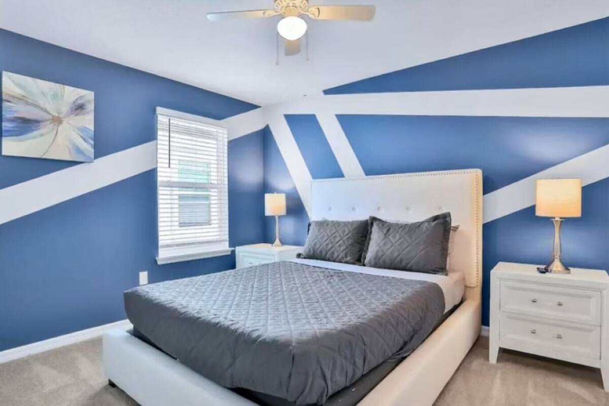 Een slaapkamer met een bed, twee nachtkastjes, een plafondventilator en een raam met jaloezieën.