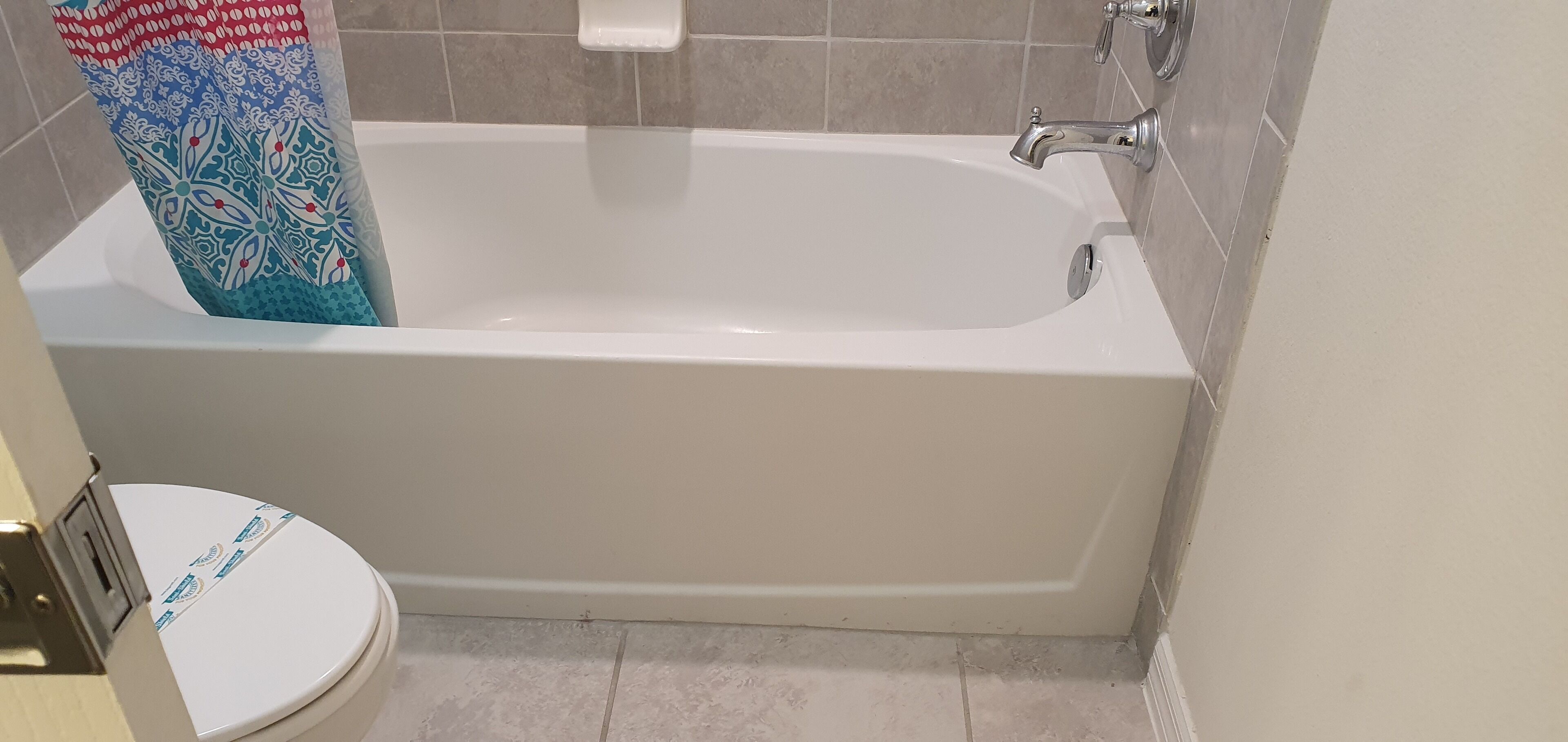A bathroom with a white bathtub, a toilet, and a shower curtain.