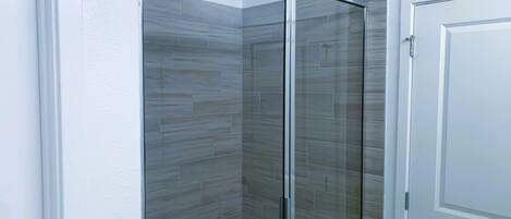 Un baño con cabina de ducha de vidrio y una puerta blanca.