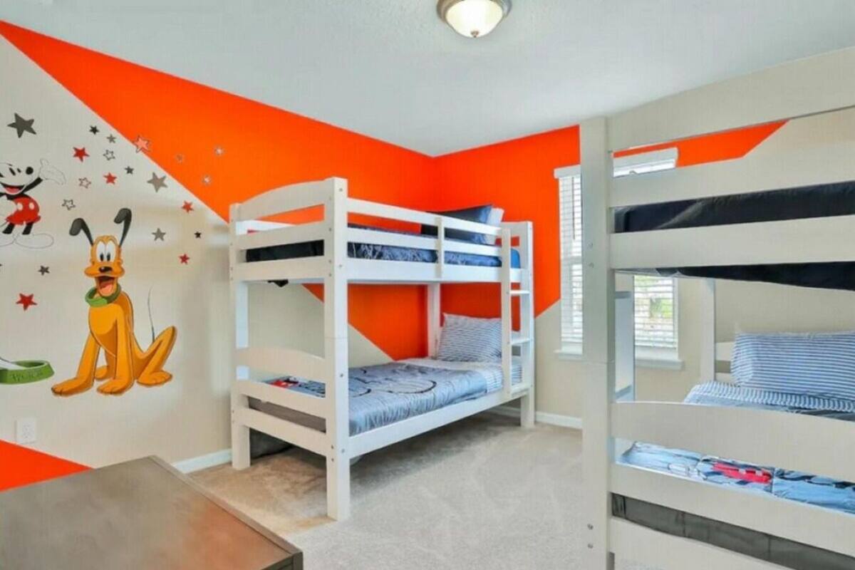 Een kamer met stapelbedden, een muurschildering en een raam.