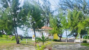 A coastal property with a yellow building, outdoor seating, and a view of the sea.