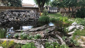 A garden with a pond, stone wall, and wooden log. - Cabin #2 - Backyard Bunkhouse
 (Irwin)