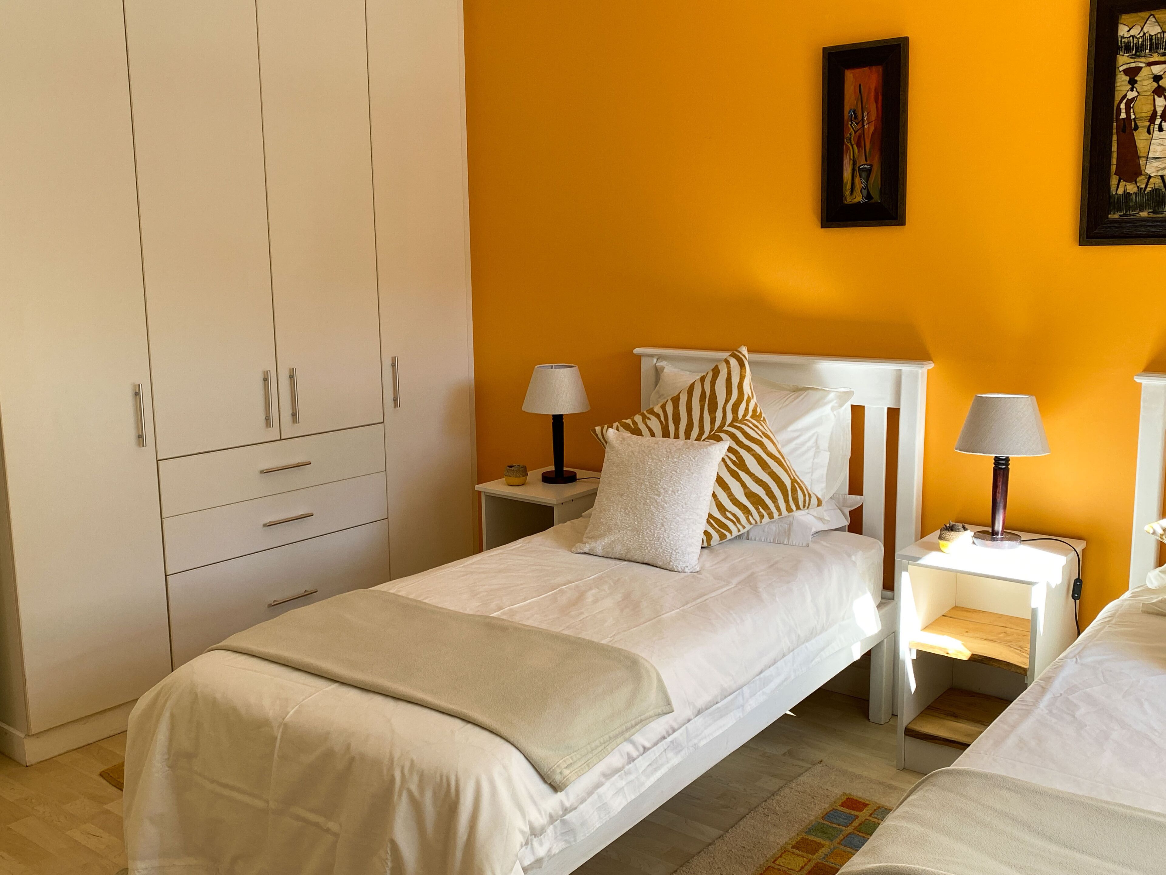 Een slaapkamer met een bed, nachtkastjes, een kledingkast en een schilderij aan de muur.