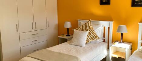 Un dormitorio con cama, mesitas de noche, un armario y un cuadro en la pared.