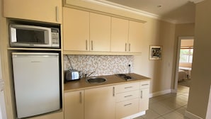 A kitchen with beige cabinets, a microwave, a toaster, and a sink.