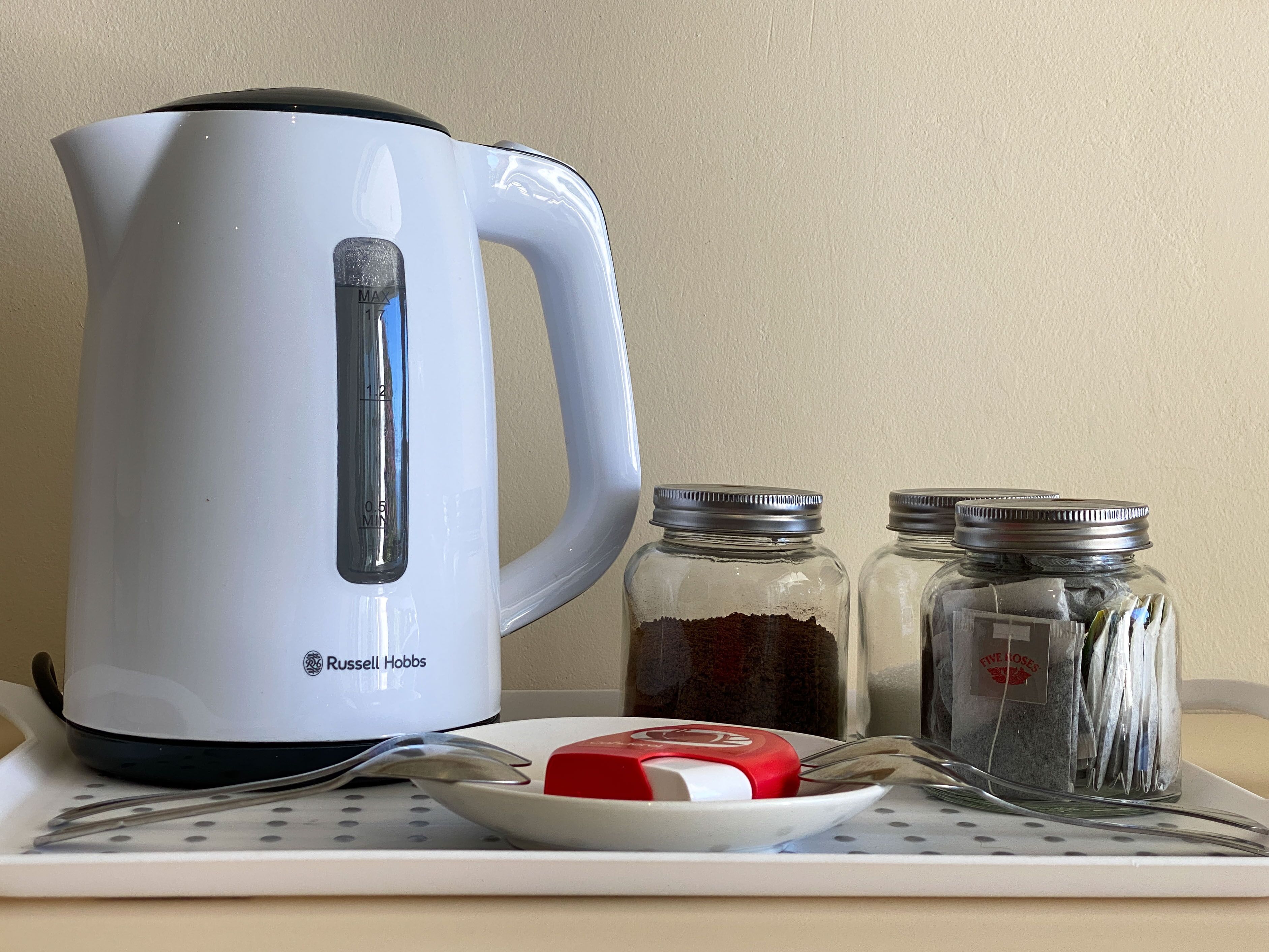En vit vattenkokare från Russell Hobbs, två glasburkar med metallock och en vit tallrik med ett rött och vitt föremål på.