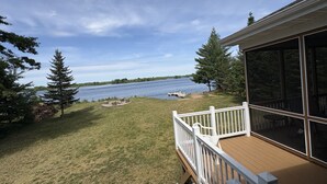Une terrasse avec vue sur un lac, entourée d’arbres et bordée d’une pelouse.