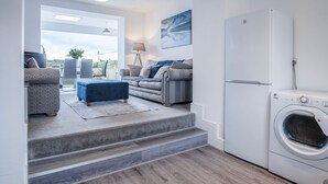 A modern living room with a sofa, ottoman, and a washing machine.