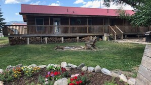 A wooden building with a red roof, a deck, and a fire pit in the yard. - Cabin #1 - Backyard Bunkhouse

 (Irwin)