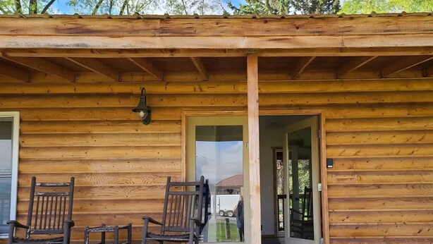 A wooden cabin with a porch, two rocking chairs, and a door leading inside. - Cabin #1 - Backyard Bunkhouse

 (Irwin)