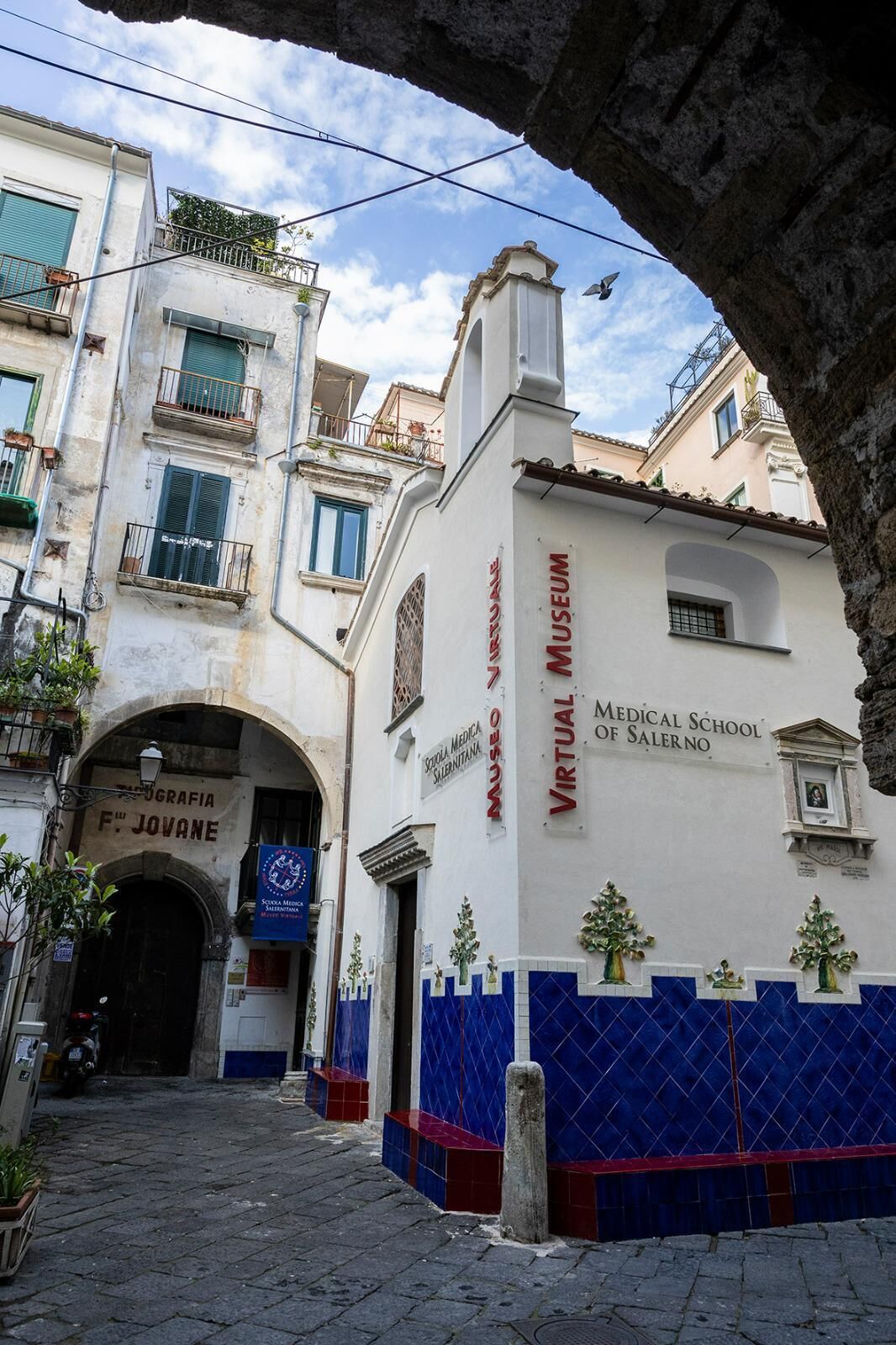 A building with a sign for the Virtual Museum of the Medical School of Salerno.