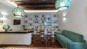 A modern kitchen with white cabinetry, a central island, and a green sofa. - B&B Boutique Epoca (Salerno)