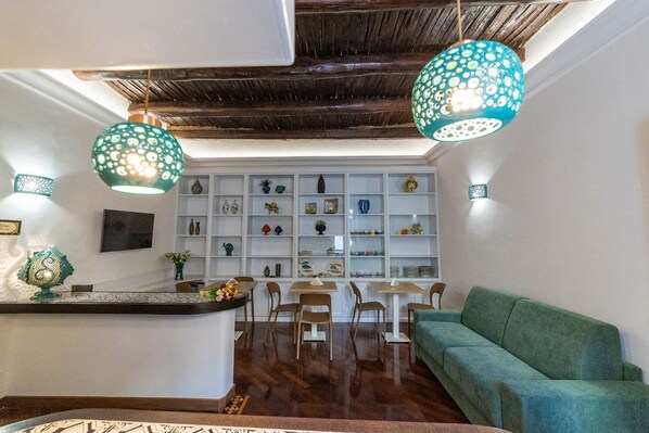 A modern kitchen with white cabinetry, a central island, and a green sofa. - B&B Boutique Epoca (Salerno)
