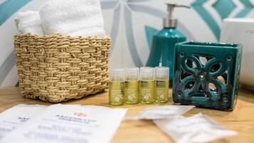 A bathroom with a woven basket containing towels, a green soap dispenser, and bottles of body wash.