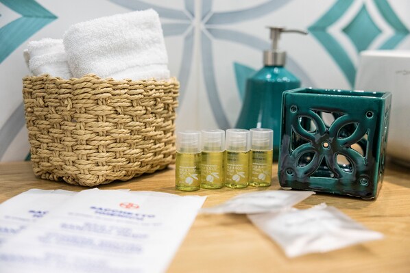 A bathroom with a woven basket containing towels, a green soap dispenser, and bottles of body wash. - B&B Boutique Epoca (Salerno)