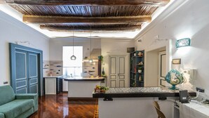 A modern kitchen with a central island, a dining area with a table and chairs, and a living room with a sofa and a coffee table. - B&B Boutique Epoca (Salerno)