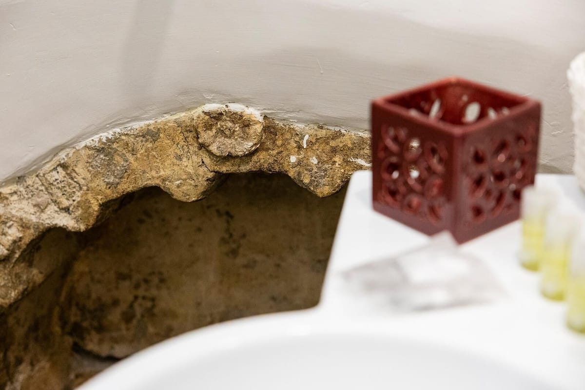 A bathroom with a stone sink, a red decorative cube, and a white countertop.