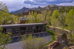 A multi-story hotel with a parking lot and a view of mountains in the background. - On the River, Downtown Estes Park, Close to RMNP Entrance (Estes Park)