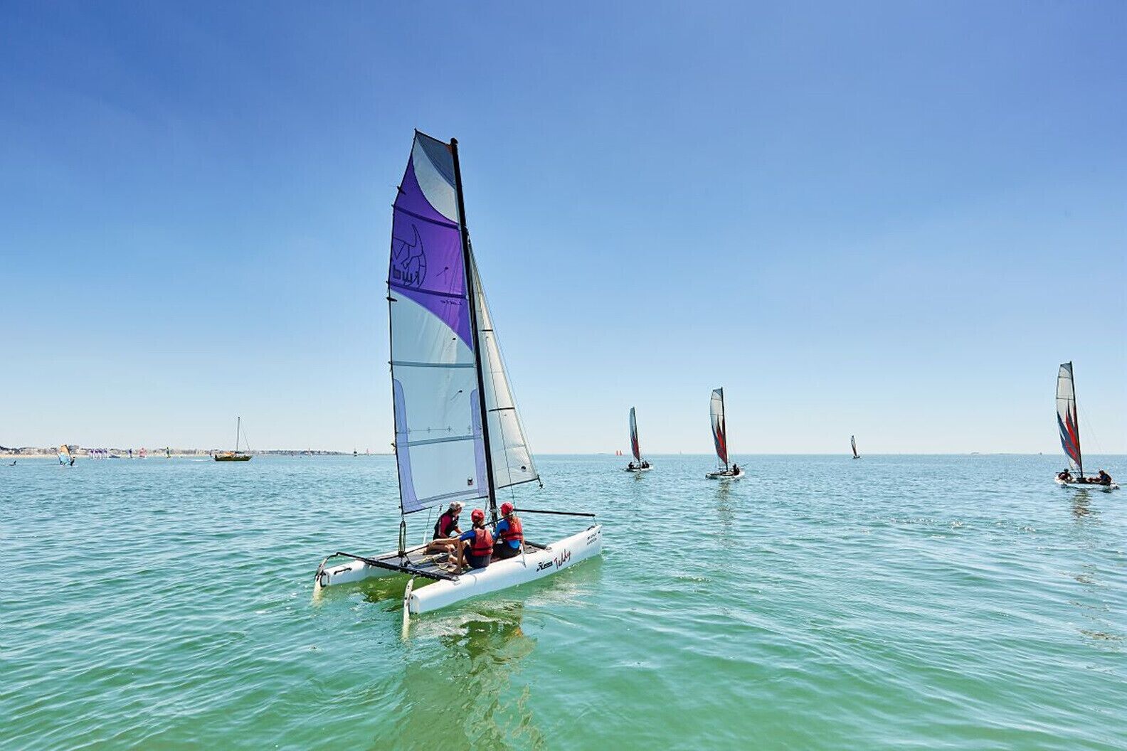 A sailboat with multiple sails on calm waters.