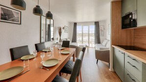 A dining area with a long table set for four, a kitchen with a microwave, and a balcony with a view. - Relaxation and harbour views in Arzon - Pool (Arzon)