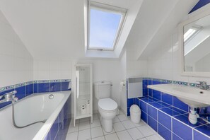 Bathroom features a bathtub, toilet, and sink with a mirror above.