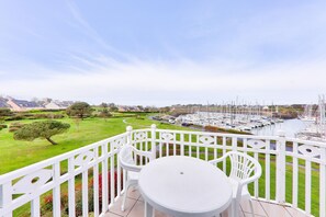Enjoy a serene view of the marina from this balcony with a table and chairs.